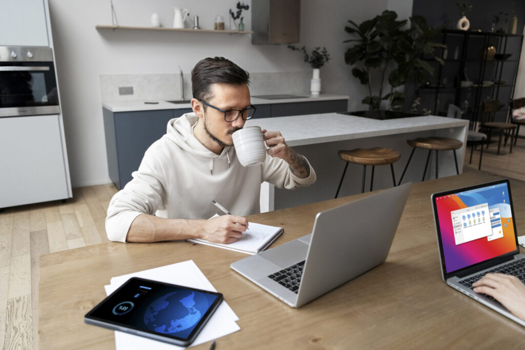 Homem estudando em casa com notebook e caderno, representando a flexibilidade dos cursos online do Instituto Aprimore.